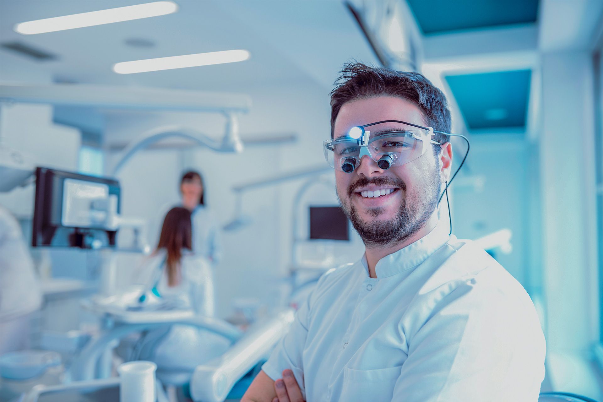 Exklusive Oberflächenveredelung für Medizintechnik-Hersteller: Junge lächelnder Zahnarzt mit Lupenbrille